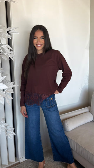 Chocolate brown top with lace detailing at the hemline and long sleeves, worn by a smiling woman.