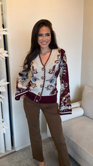 Multicolor knit cardigan with floral patterns, buttoned front, and long sleeves modeled by a woman.