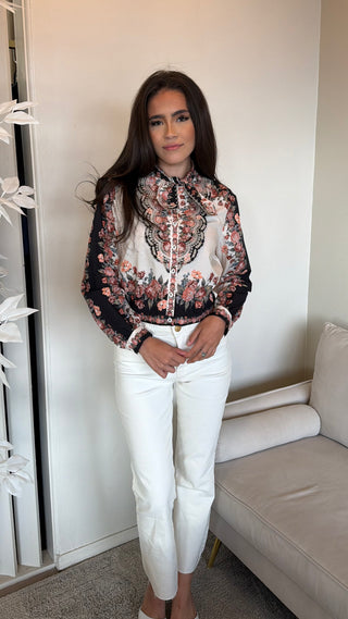 A woman wearing a Farm Rio long sleeve shirt with a winter floral pattern, paired with white pants.