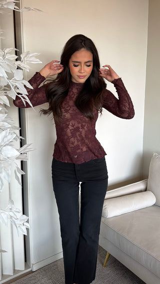 Burgundy lace top with a high neckline and long sleeves, worn by a model.