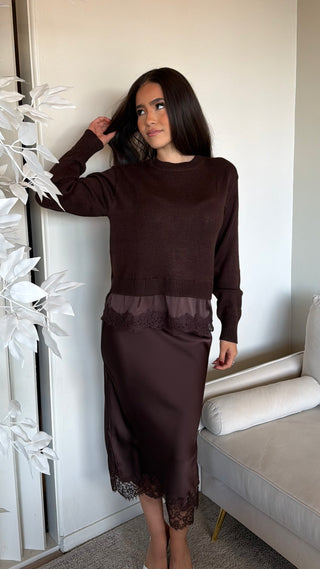 A woman wearing a chocolate brown sweater with lace trim, paired with a matching skirt.