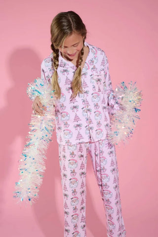 Child wearing a pink pajama set with festive Santa and holiday motifs, holding a decorative garland.